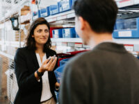 Young female professional explains something to man in a storage