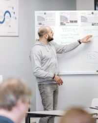 Mann zeigt etwas an einem Whiteboard. Workshop.